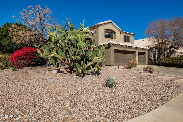 mediterranean / spanish home with a garage, a tile roof, concrete driveway, and stucco siding