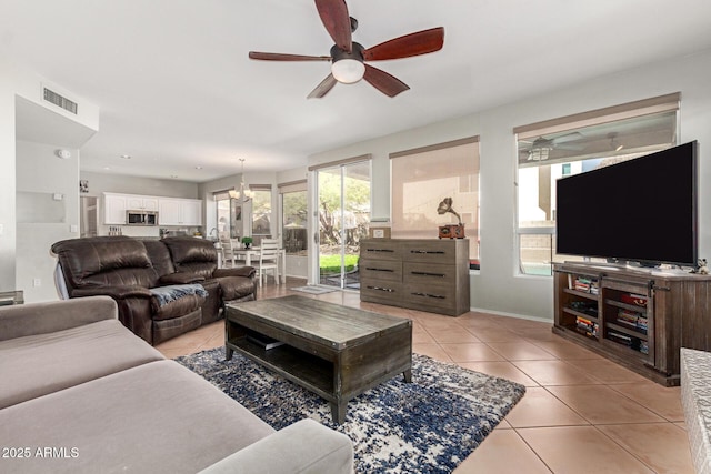 living room featuring light tile patterned floors, ceiling fan, visible vents, and baseboards