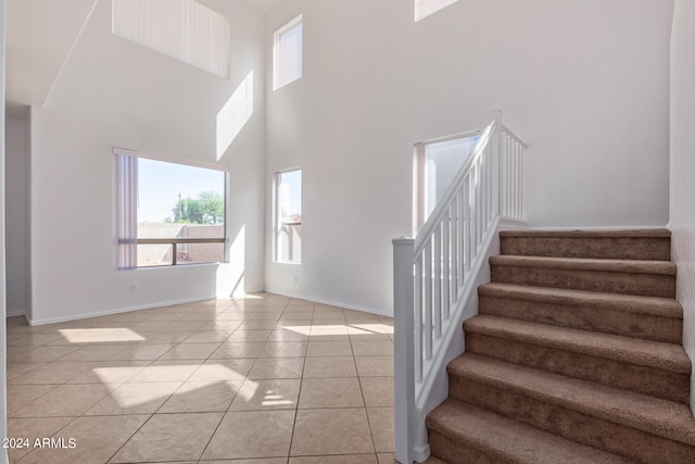 staircase featuring a towering ceiling and tile patterned floors