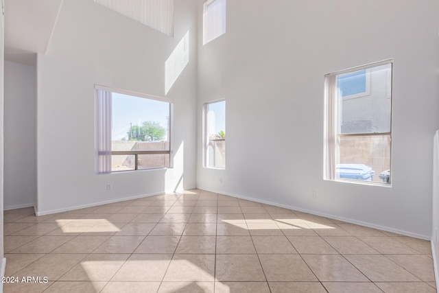 empty room with a high ceiling and light tile patterned flooring