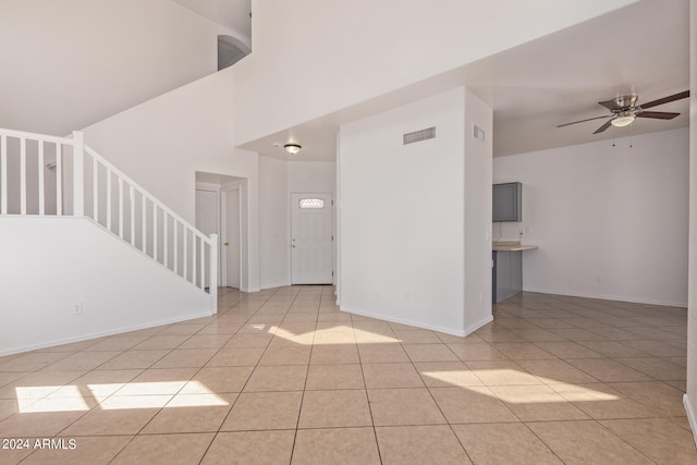 tiled empty room featuring high vaulted ceiling and ceiling fan