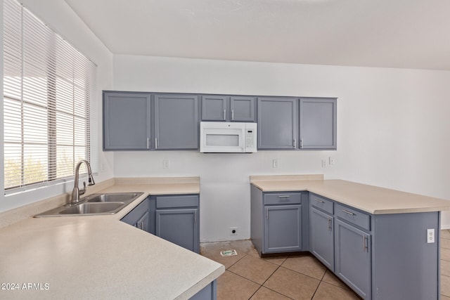 kitchen featuring kitchen peninsula, sink, light tile patterned floors, and gray cabinets