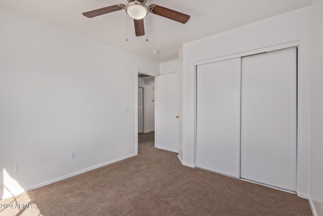 unfurnished bedroom featuring a closet, ceiling fan, and carpet flooring