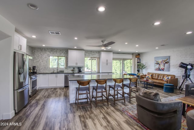 kitchen featuring appliances with stainless steel finishes, sink, wood-type flooring, a center island, and white cabinetry