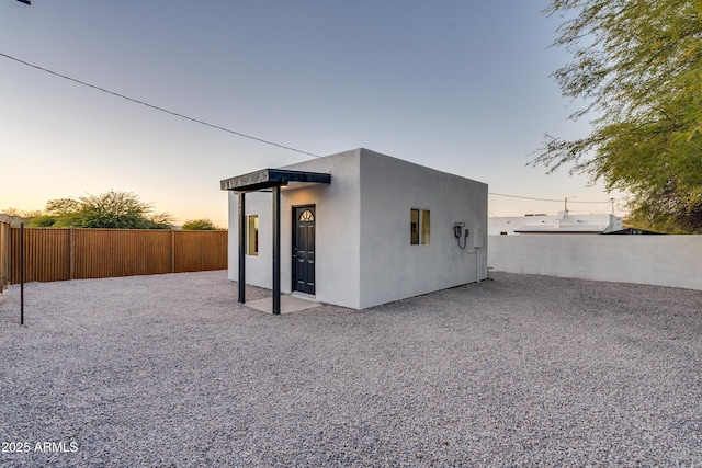 back house at dusk featuring a patio area