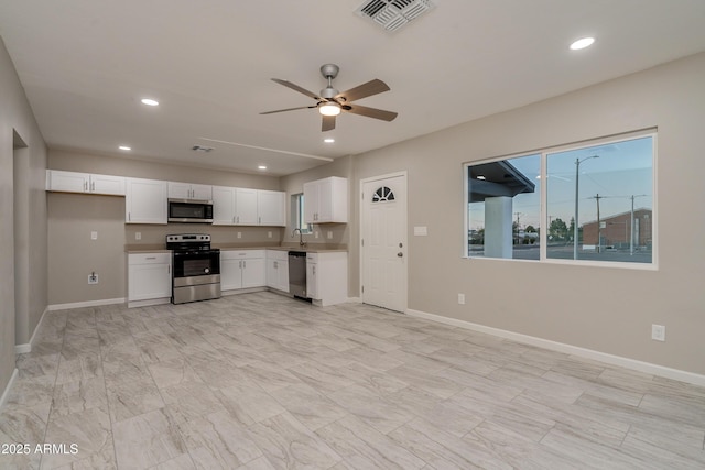 kitchen with appliances with stainless steel finishes, white cabinets, and ceiling fan