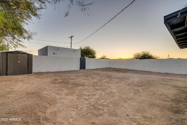 yard at dusk featuring a storage unit