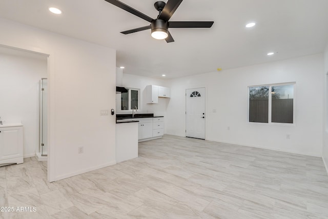 unfurnished living room featuring sink and ceiling fan