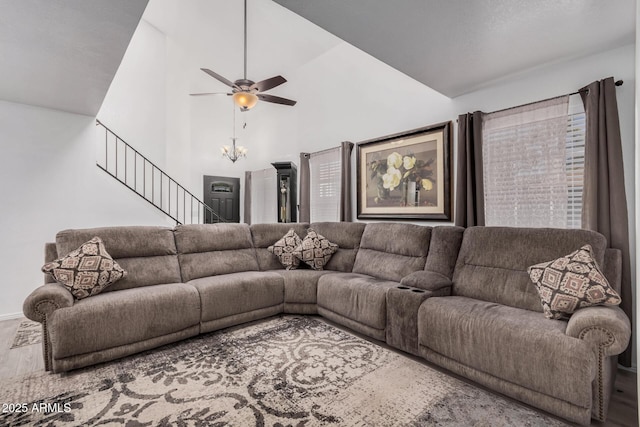 living room featuring ceiling fan with notable chandelier and vaulted ceiling