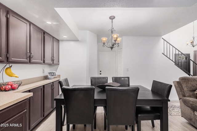 dining area with light hardwood / wood-style flooring and a notable chandelier