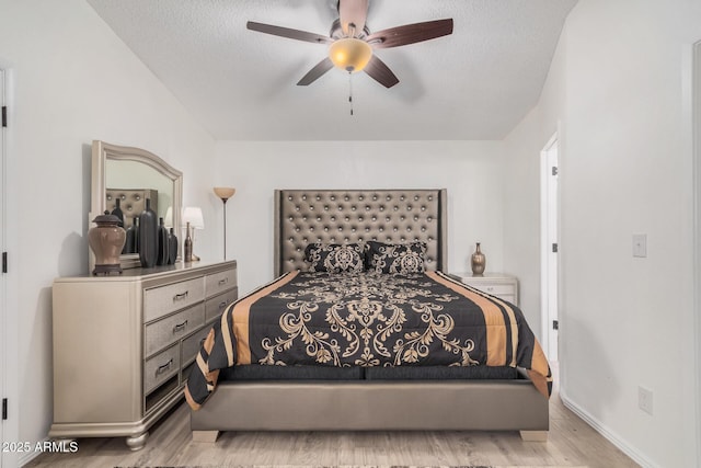 bedroom featuring ceiling fan, light hardwood / wood-style floors, and a textured ceiling