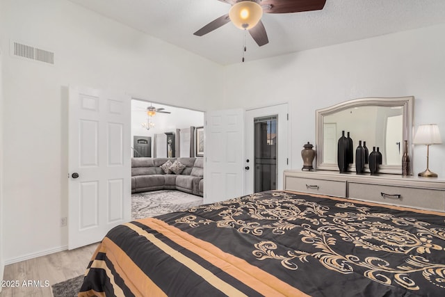 bedroom with ceiling fan, light hardwood / wood-style flooring, and a towering ceiling