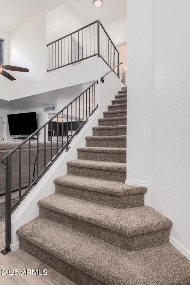 stairway featuring ceiling fan and wood-type flooring