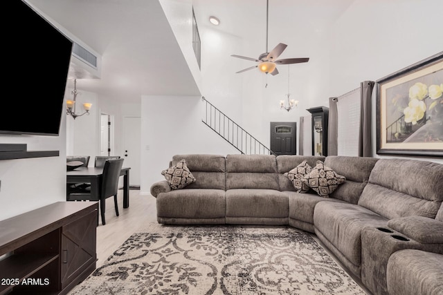 living room with ceiling fan with notable chandelier and light hardwood / wood-style floors