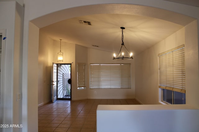 tiled foyer entrance featuring vaulted ceiling and a chandelier