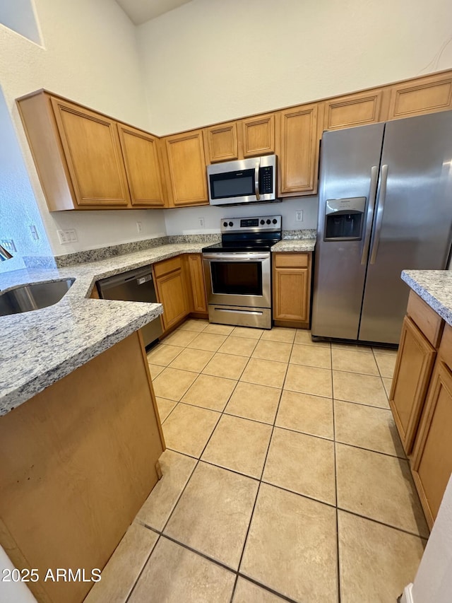 kitchen featuring light stone counters, light tile patterned floors, a towering ceiling, appliances with stainless steel finishes, and sink