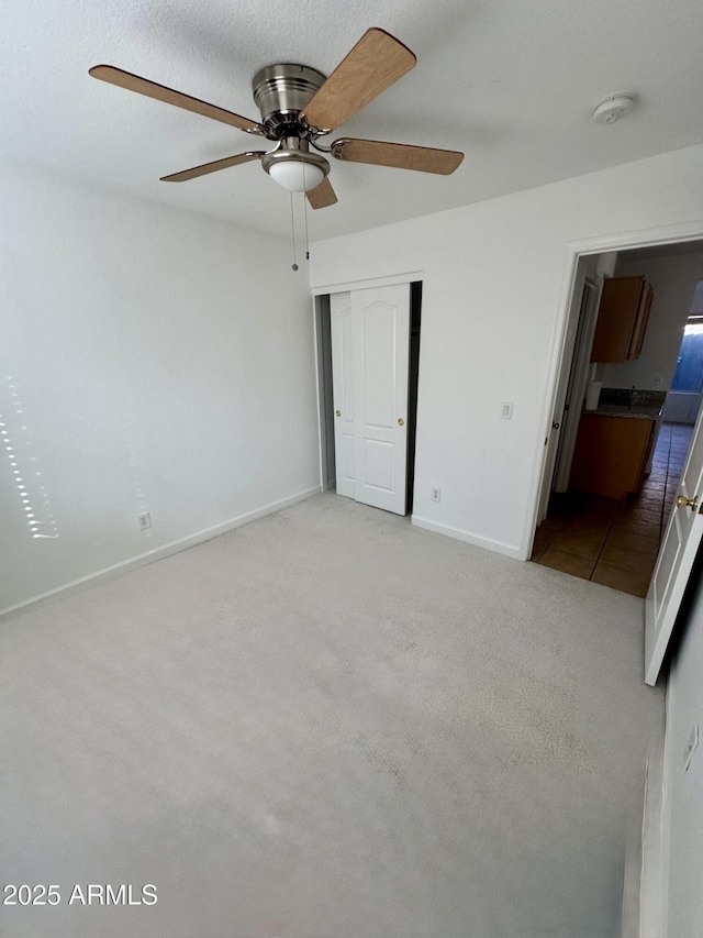 unfurnished bedroom featuring light colored carpet, ceiling fan, and a closet