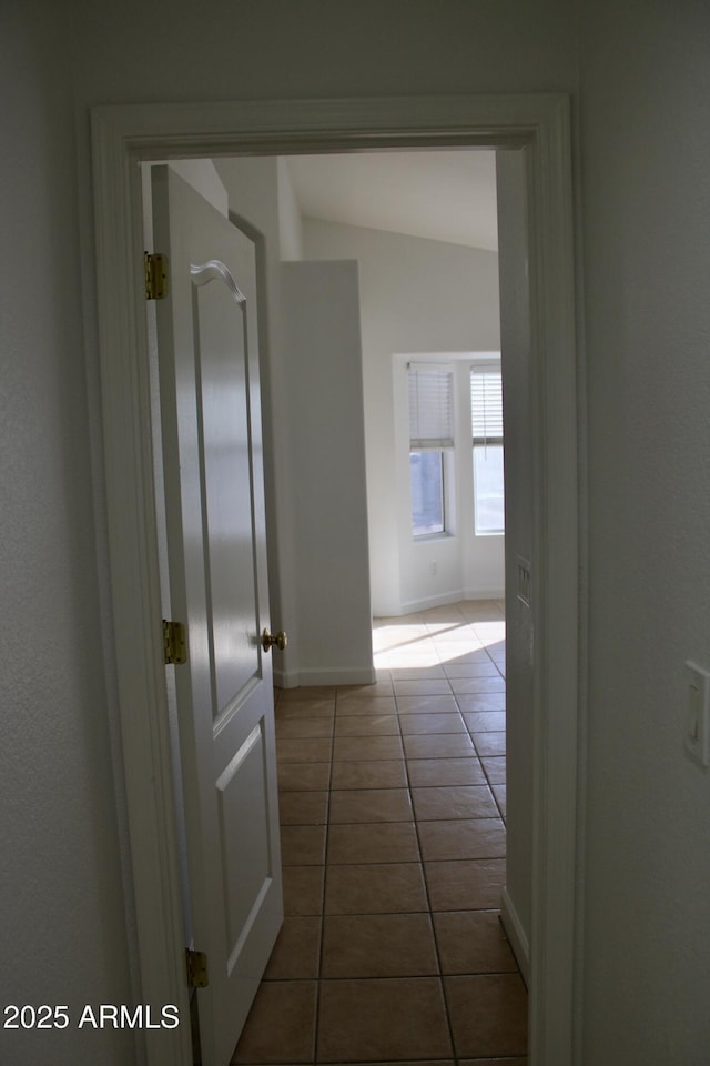 hallway featuring lofted ceiling and tile patterned floors