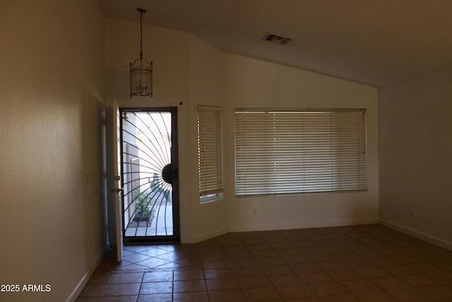 foyer entrance with lofted ceiling and dark tile patterned flooring