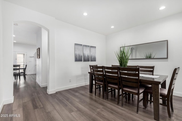 dining room featuring recessed lighting, arched walkways, dark wood-style flooring, and baseboards