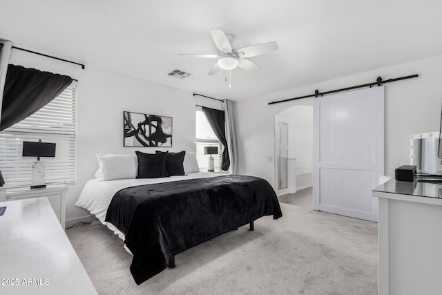 bedroom with a ceiling fan, visible vents, ensuite bath, light carpet, and a barn door