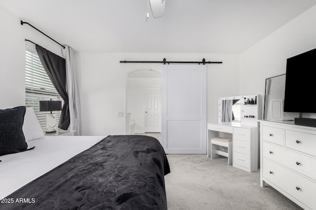 bedroom with a barn door and light colored carpet