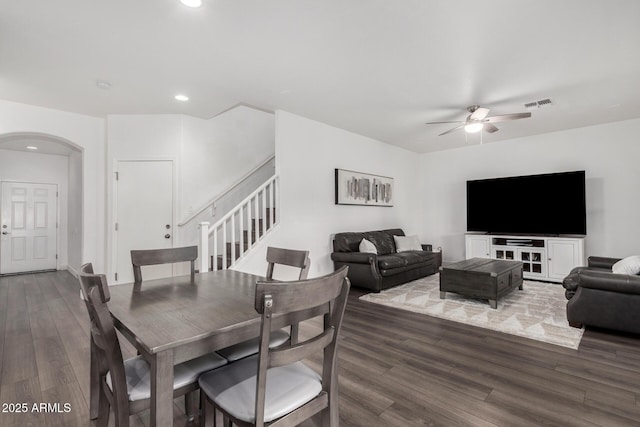 dining area featuring stairs, wood finished floors, a ceiling fan, and arched walkways