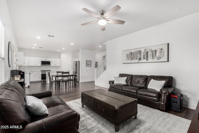 living room with stairs, wood finished floors, visible vents, and ceiling fan