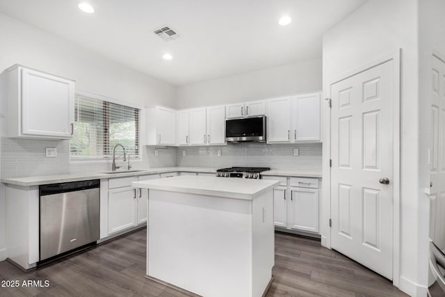 kitchen with visible vents, dark wood-type flooring, a sink, stainless steel appliances, and light countertops