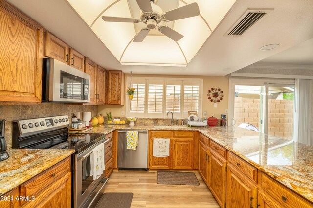 kitchen featuring appliances with stainless steel finishes, plenty of natural light, light hardwood / wood-style flooring, and ceiling fan