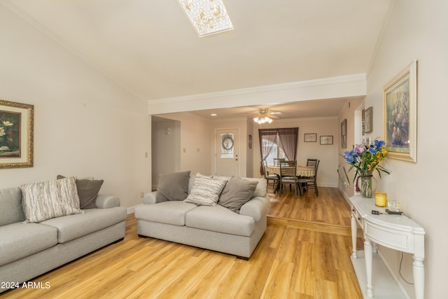 living room featuring ceiling fan, ornamental molding, light wood-type flooring, and lofted ceiling with skylight