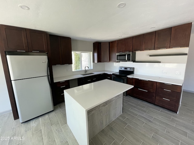 kitchen featuring light countertops, appliances with stainless steel finishes, dark brown cabinetry, and a sink