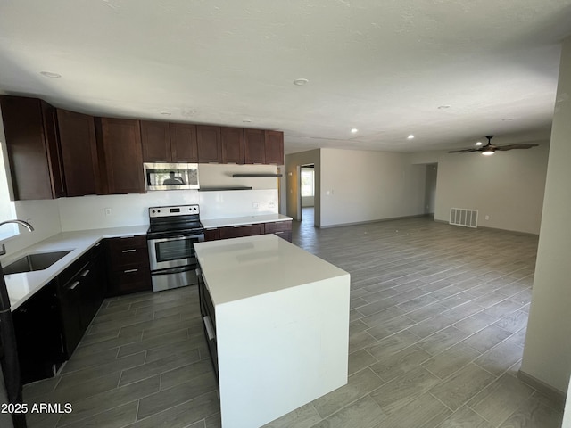 kitchen featuring recessed lighting, visible vents, a sink, a kitchen island, and appliances with stainless steel finishes