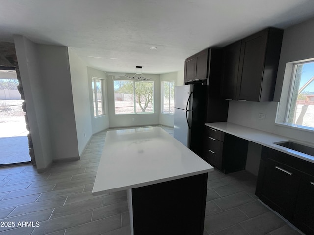 kitchen with freestanding refrigerator, light countertops, a wealth of natural light, and a kitchen island