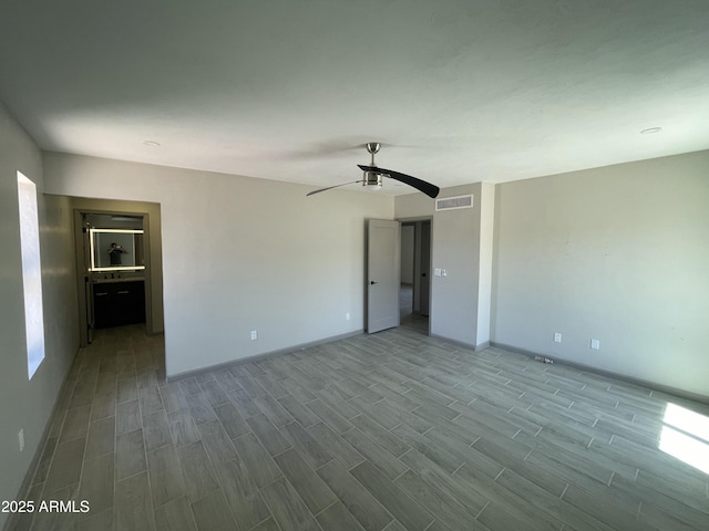unfurnished room featuring ceiling fan, baseboards, visible vents, and wood finished floors