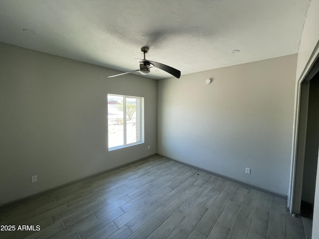 spare room with dark wood-type flooring, baseboards, and a ceiling fan