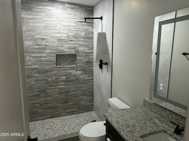 full bathroom featuring vanity, toilet, and tiled shower