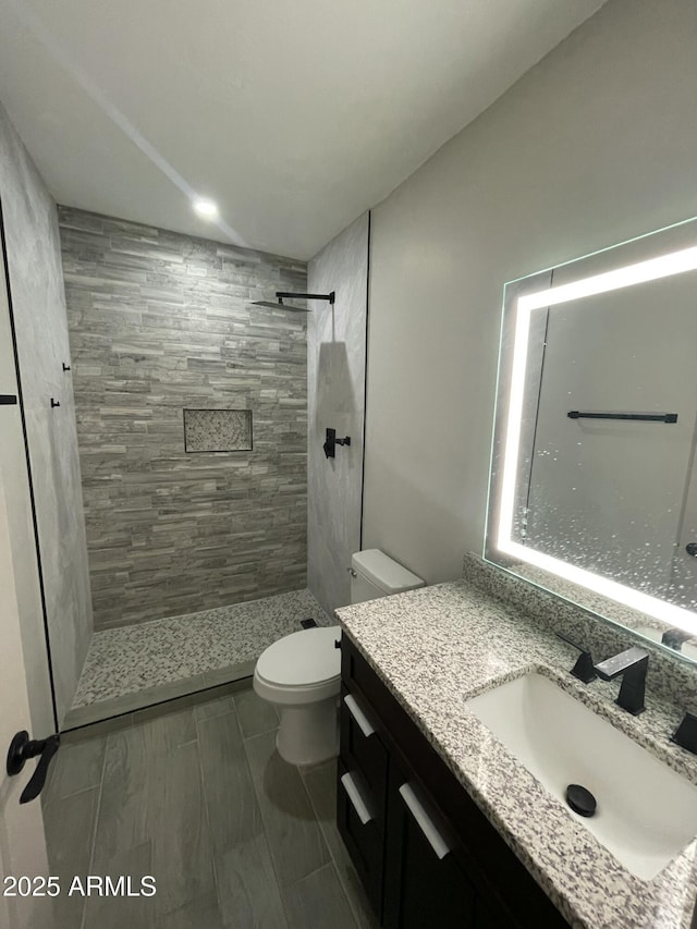 bathroom featuring vanity, toilet, and tiled shower