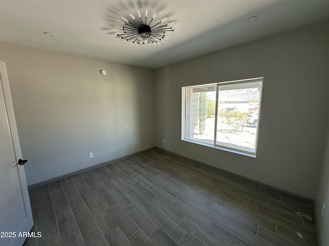 spare room with baseboards and dark wood-style flooring