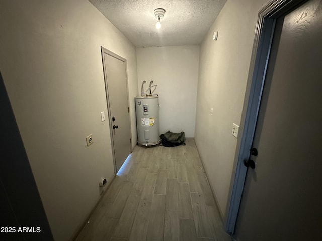 hallway featuring electric water heater, a textured ceiling, and light wood-style flooring