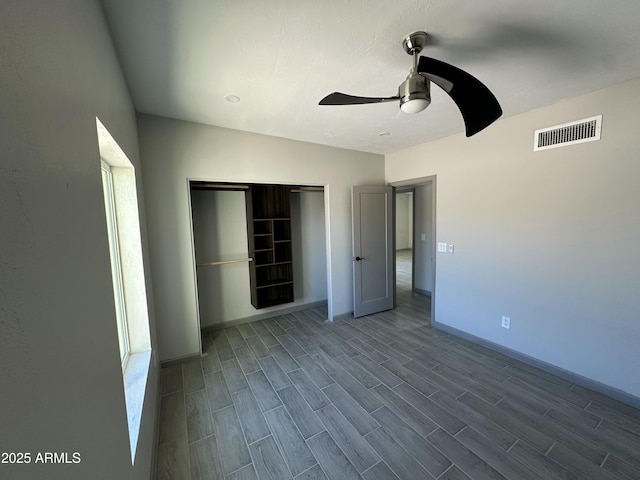 unfurnished bedroom with a closet, baseboards, visible vents, and wood finished floors