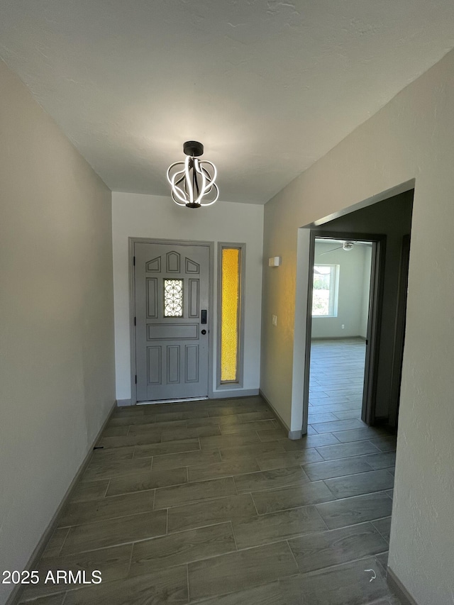 foyer entrance with baseboards, a chandelier, and wood finish floors