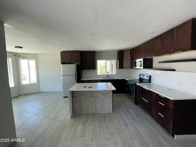 kitchen featuring freestanding refrigerator, light wood-style floors, electric range oven, and a sink