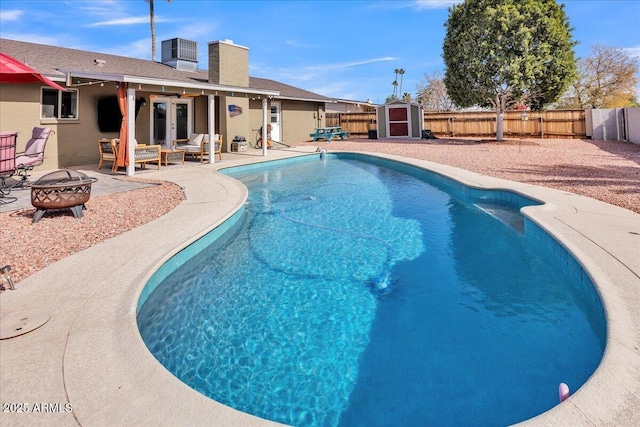 view of swimming pool featuring an outdoor fire pit, a fenced backyard, french doors, a fenced in pool, and a patio area