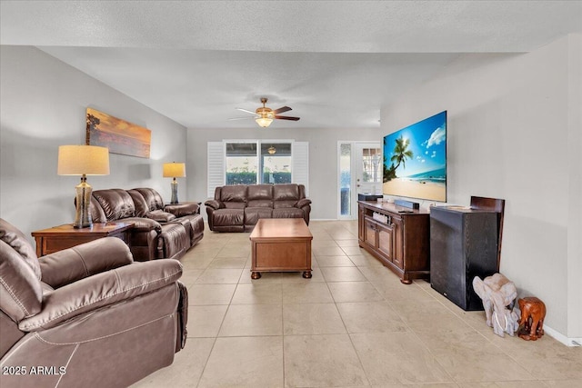 living area featuring light tile patterned floors, ceiling fan, baseboards, and a textured ceiling