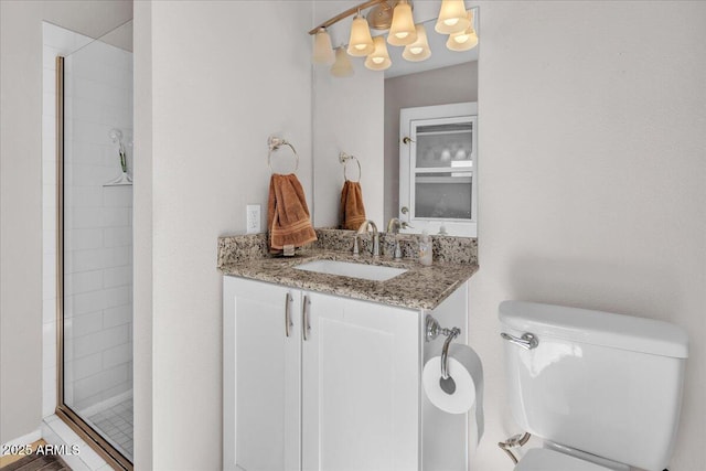 bathroom featuring a tile shower, vanity, and toilet