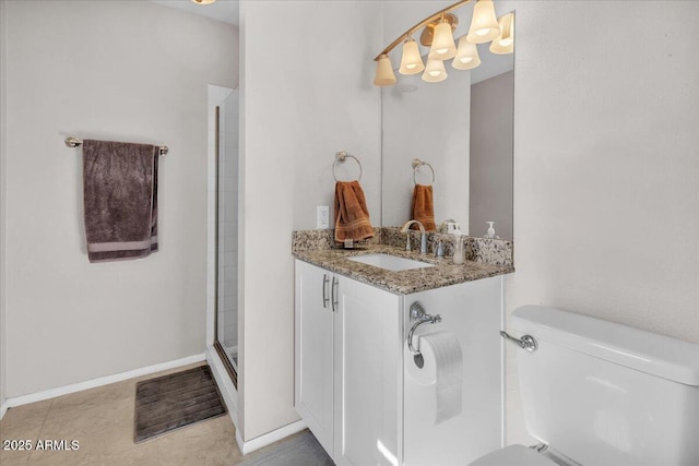 bathroom featuring toilet, a shower stall, vanity, baseboards, and tile patterned floors