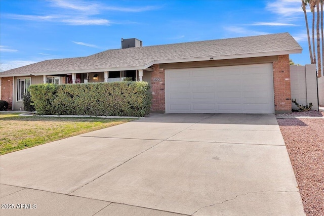 ranch-style house featuring driveway, brick siding, roof with shingles, and an attached garage