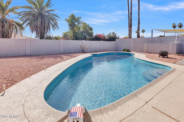 view of swimming pool with a fenced backyard and a fire pit