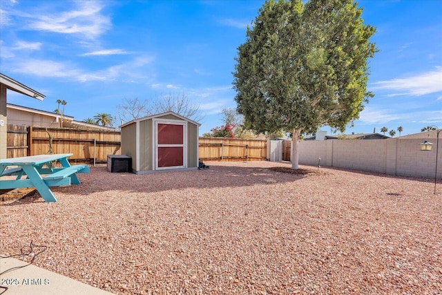 view of yard with a shed, a fenced backyard, and an outbuilding